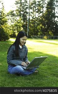 A girl sitting in a park with laptop