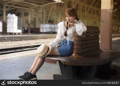 A girl sitting on a vintage chair While waiting for the train at the train station