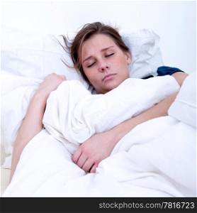 A girl sleeping in a bed with white sheets.