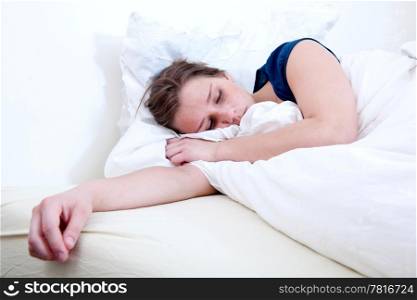 A girl sleeping in a bed with white sheets.
