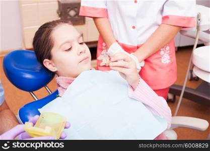 A girl tries to establish a retainer for Teeth Dental Braces, sitting in a dental chair