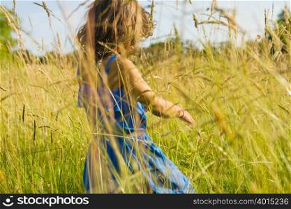 A girl walking through a field of long grass