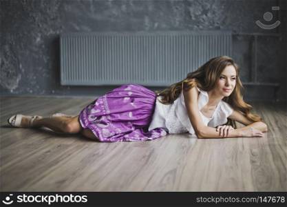 A girl with long brown hair posing on the parquet floor.. The slender girl lying on the parquet floor 6932.