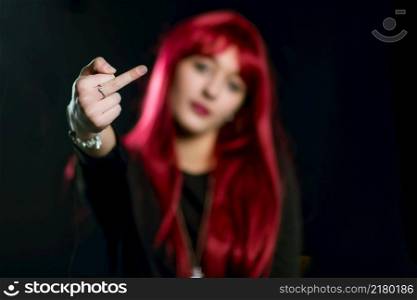 A girl with red hair does the middle finger on a black background