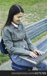 A girl working on her laptop at a park