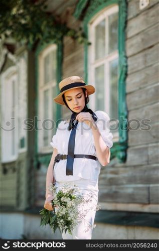 A girls summer walk against the background of an ancient city.. A girl in a hat and a white blouse walks against the background of old woo