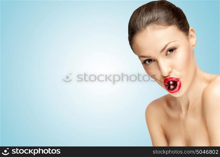 A glamorous chic brunette sedusively holding a sweet cherry in her mouth.
