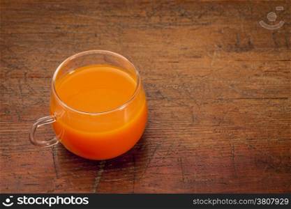 a glass cup of home made carrot juice on a grunge wooden table