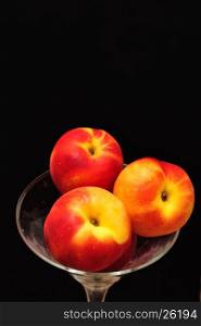 A glass filled with nectarines isolated on a black background