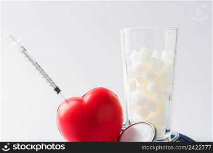 A glass full of white sugar cube sweet food ingredient and doctor stethoscope, studio shot isolated on white background, health high blood risk of diabetes and calorie intake concept and unhealthy drink