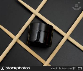 a glass jar for cosmetics lies on a black background. Natural cometic. Product branding, top view