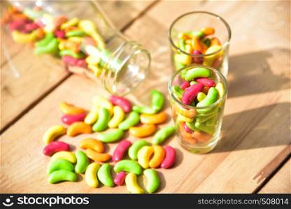 a glass jar full of colored candies on wood background