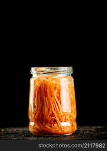 A glass jar with canned carrots. On a black background. High quality photo. A glass jar with canned carrots.