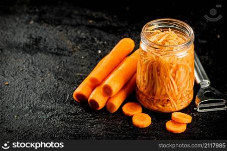 A glass jar with canned carrots. On a black background. High quality photo. A glass jar with canned carrots.
