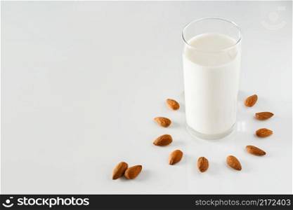 A glass of almond milk on a white background. Lactose-free vegetable diet milk. Gluten free almond drink on a blue background. Super Food - A glass of almond milk for a healthy diet. Trending food, vertical photo. Place for your text.. A glass of almond milk on a white background. Lactose-free vegetable diet milk.