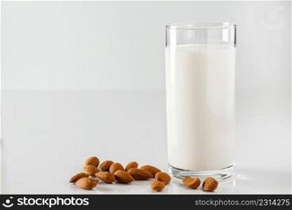 A glass of almond milk on a white background. Lactose-free vegetable diet milk. Gluten free almond drink on a blue background. Super Food - A glass of almond milk for a healthy diet. Trending food, vertical photo. Place for your text.. Super Food - A glass of almond milk for a healthy diet. Trending food, vertical photo. Place for your text.