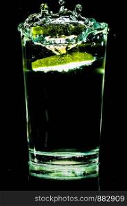 A glass of cold water with slices of lemon making a splash