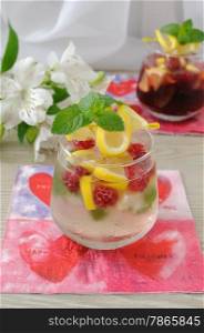 A glass of fresh homemade lemonade with mint and raspberries