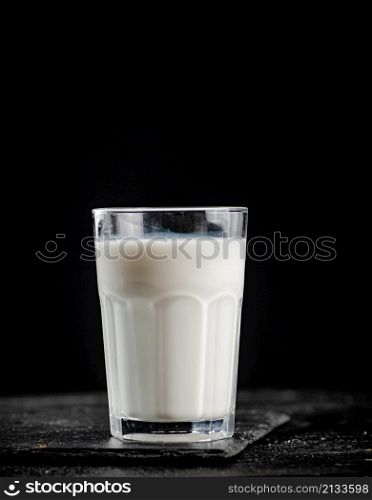 A glass of fresh milk on a stone board. On a black background. High quality photo. A glass of fresh milk on a stone board.
