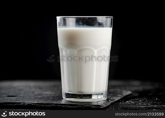 A glass of fresh milk on a stone board. On a black background. High quality photo. A glass of fresh milk on a stone board.