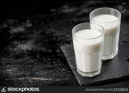 A glass of fresh milk on a stone board. On a black background. High quality photo. A glass of fresh milk on a stone board.