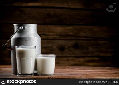A glass of homemade village milk. On a wooden background. High quality photo. A glass of homemade village milk.