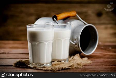 A glass of homemade village milk. On a wooden background. High quality photo. A glass of homemade village milk.