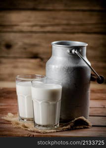 A glass of homemade village milk. On a wooden background. High quality photo. A glass of homemade village milk.