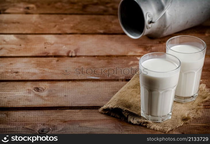 A glass of homemade village milk. On a wooden background. High quality photo. A glass of homemade village milk.