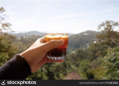 A glass of ice americano in cafe mountain background