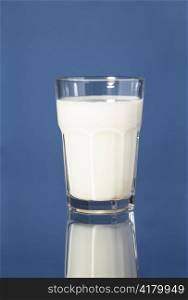 A Glass of milk on blue reflective surface