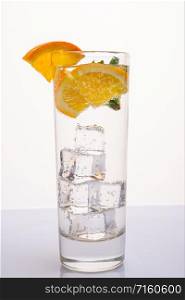 A glass of mineral water decorated with a slice of orange and mint. A glass of mineral water with an orange slice and mint