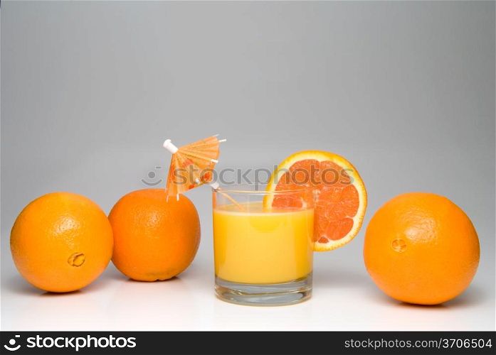 A glass of orange juice with an umbrella and slice.