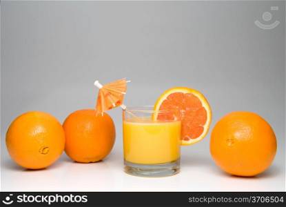A glass of orange juice with an umbrella and slice.