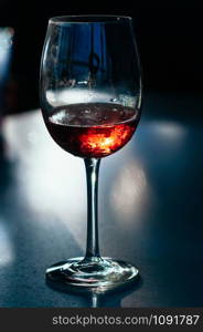 A glass of red wine on the table on dark blue background. Wine in a fogged up glass on a bar table, beautiful flecks and reflections from back light. Party, event, wine tasting, lounge concept