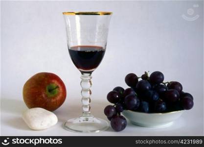 A glass of red wine with fruits isolated on white