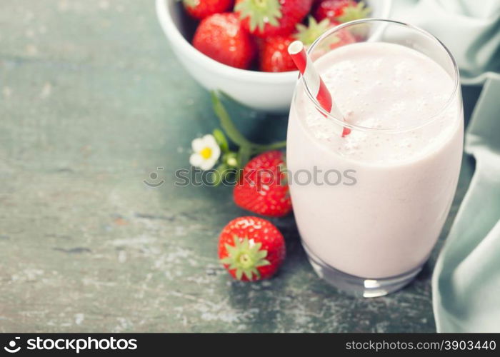 A glass of strawberry smoothie on a wooden background