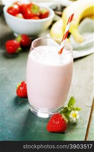 A glass of strawberry smoothie on a wooden background