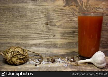 A glass of tomato juice with garlic and spices on wooden background.