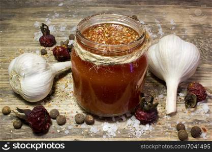 A glass of tomato juice with garlic and spices on wooden background.