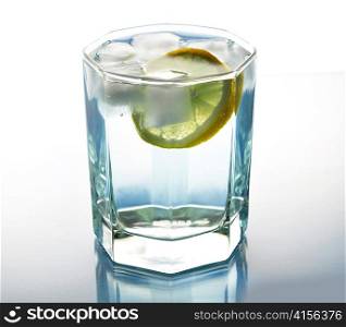 a glass of water with ice and lemon , close up