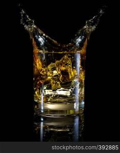 A glass of whiskey and splash isolated on a black background. A glass of whiskey and splash