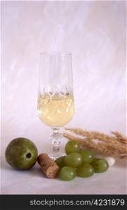 A glass of white wine and grapes on textured, painted background