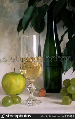 A glass of white wine and grapes on textured, painted background