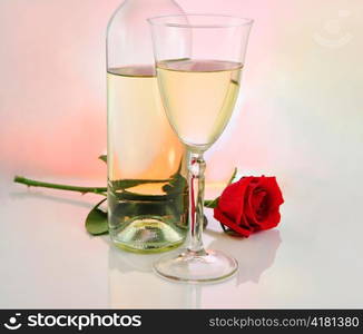 a glass of white wine with bottle and rose