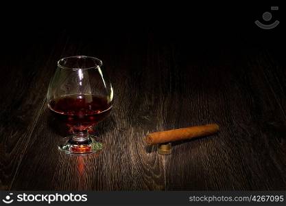 a glass with cognac and a cigar