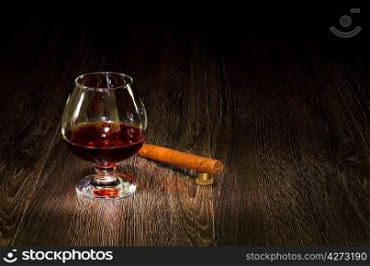 a glass with cognac and a cigar