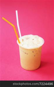 A glass with frappuccino coffee cocktail, cold refreshing drink or beverage with ice on red background