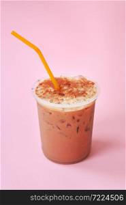A glass with ice coffee cocktail, cold refreshing drink or beverage with ice on pink background