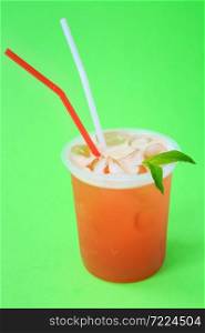 A glass with red lemonade with mint, cold refreshing drink or beverage with ice on green background